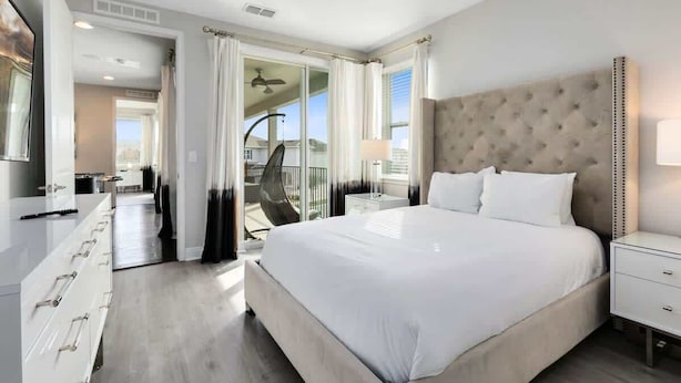 Une chambre avec un grand lit, une table de chevet, une armoire et une vue sur le balcon.