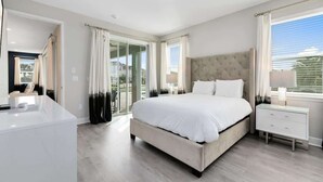 Une chambre à coucher avec un grand lit, une table de chevet, une commode et une vue sur l’extérieur.