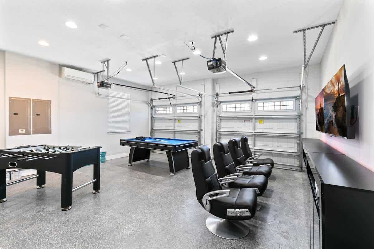 Una habitación con mesa de billar, mesa de futbolín y sillones de masaje.