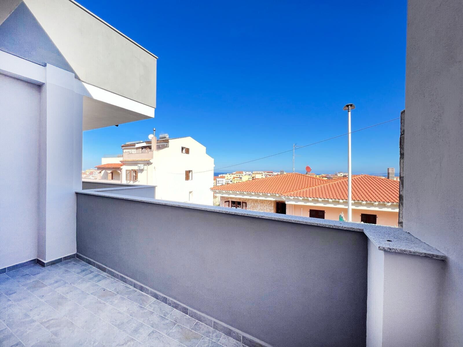 A balcony with a clear view of neighboring buildings and a streetlight.