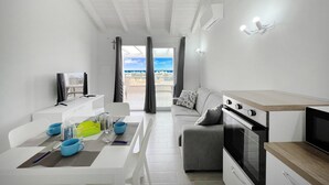 A modern, well-lit living room with a dining area, a grey sofa, and a kitchen with a built-in oven and microwave. - Affittimoderni Castelsardo The Sun - CSSO11 (Castelsardo)
