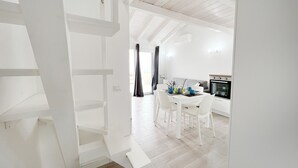 A modern, white interior with a staircase leading to a dining area and kitchen. - Affittimoderni Castelsardo The Sun - CSSO11 (Castelsardo)