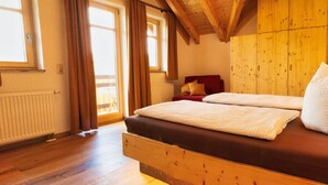 A wooden bed with a mattress and pillows in a room with wooden beams and a window.