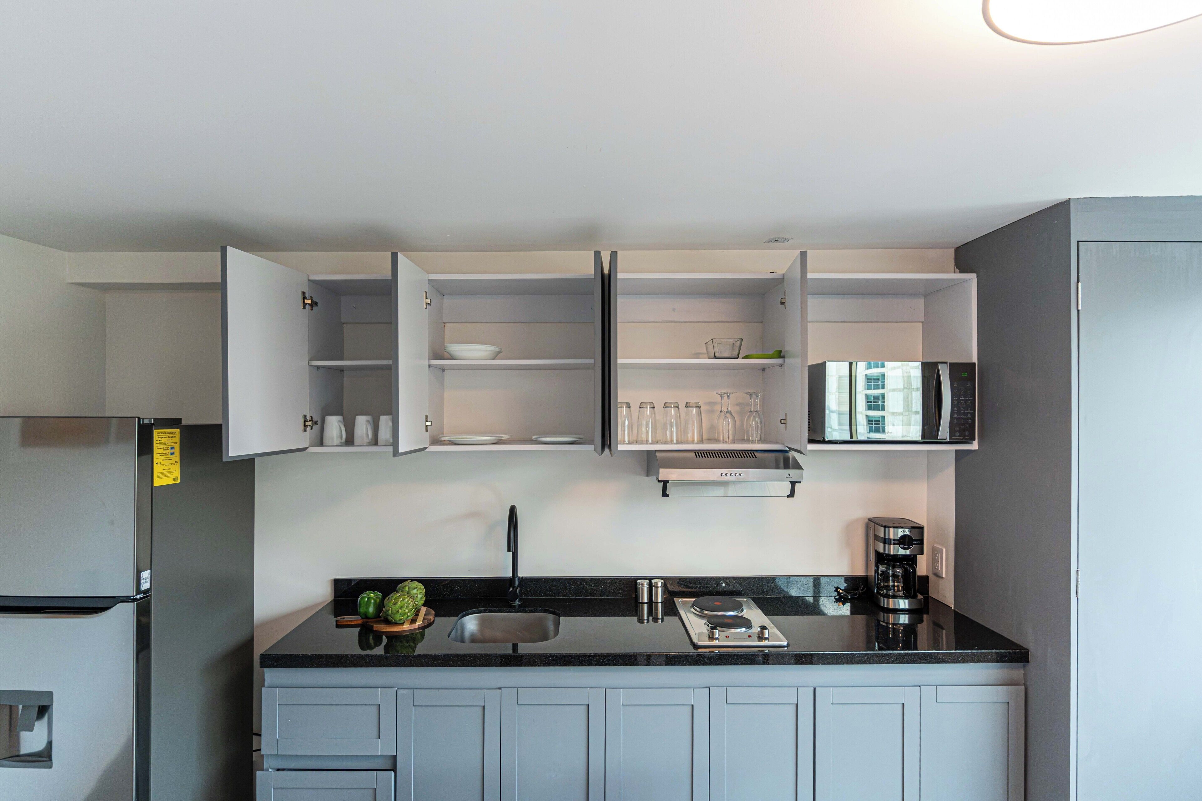 A modern kitchen with a built-in microwave, a coffee maker, and a sink.