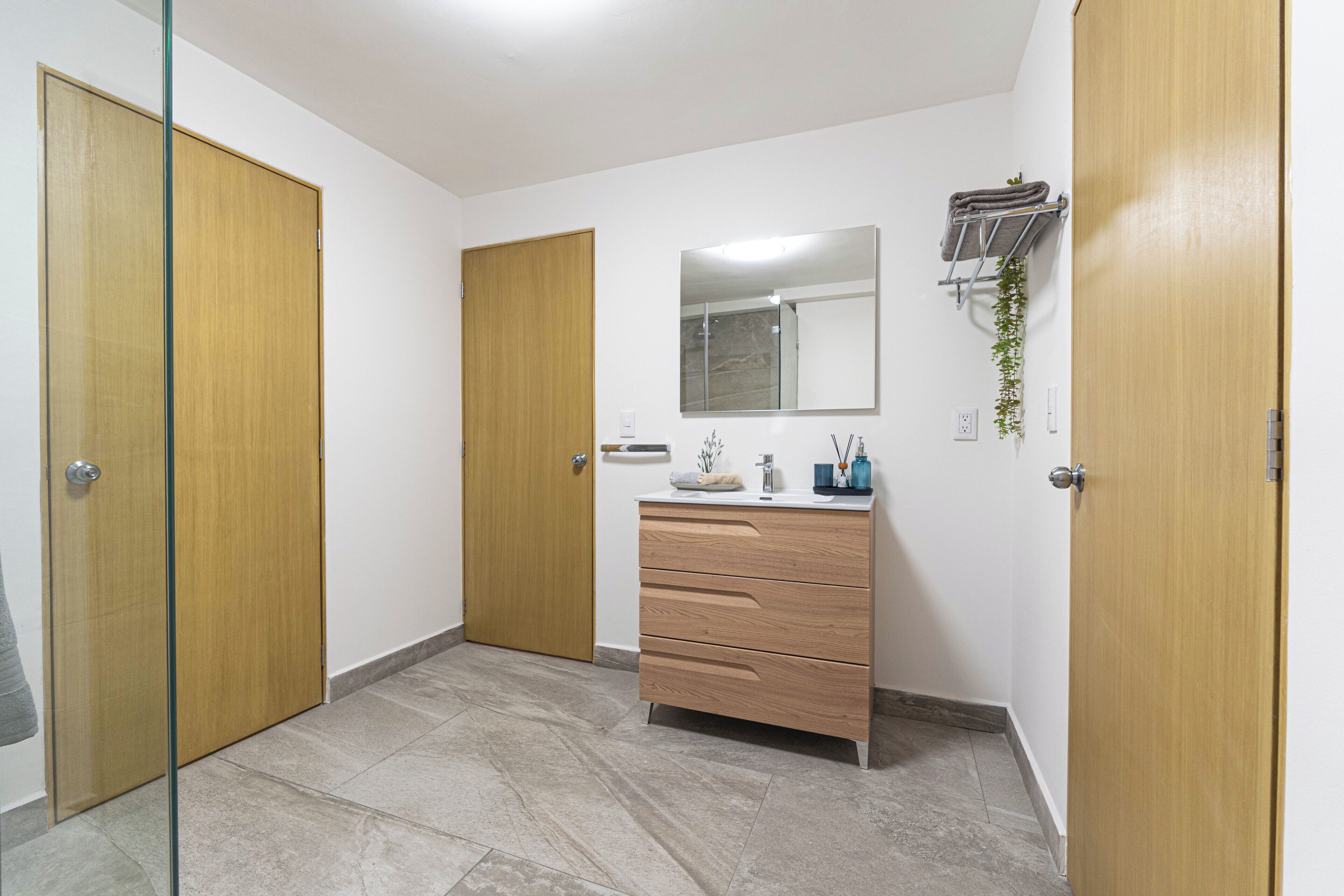 Une salle de bain avec un meuble-lavabo en bois, un miroir et un porte-serviettes.