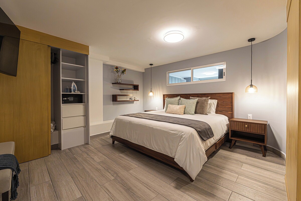A modern bedroom with a bed, bedside tables, a wardrobe, and built-in shelves.