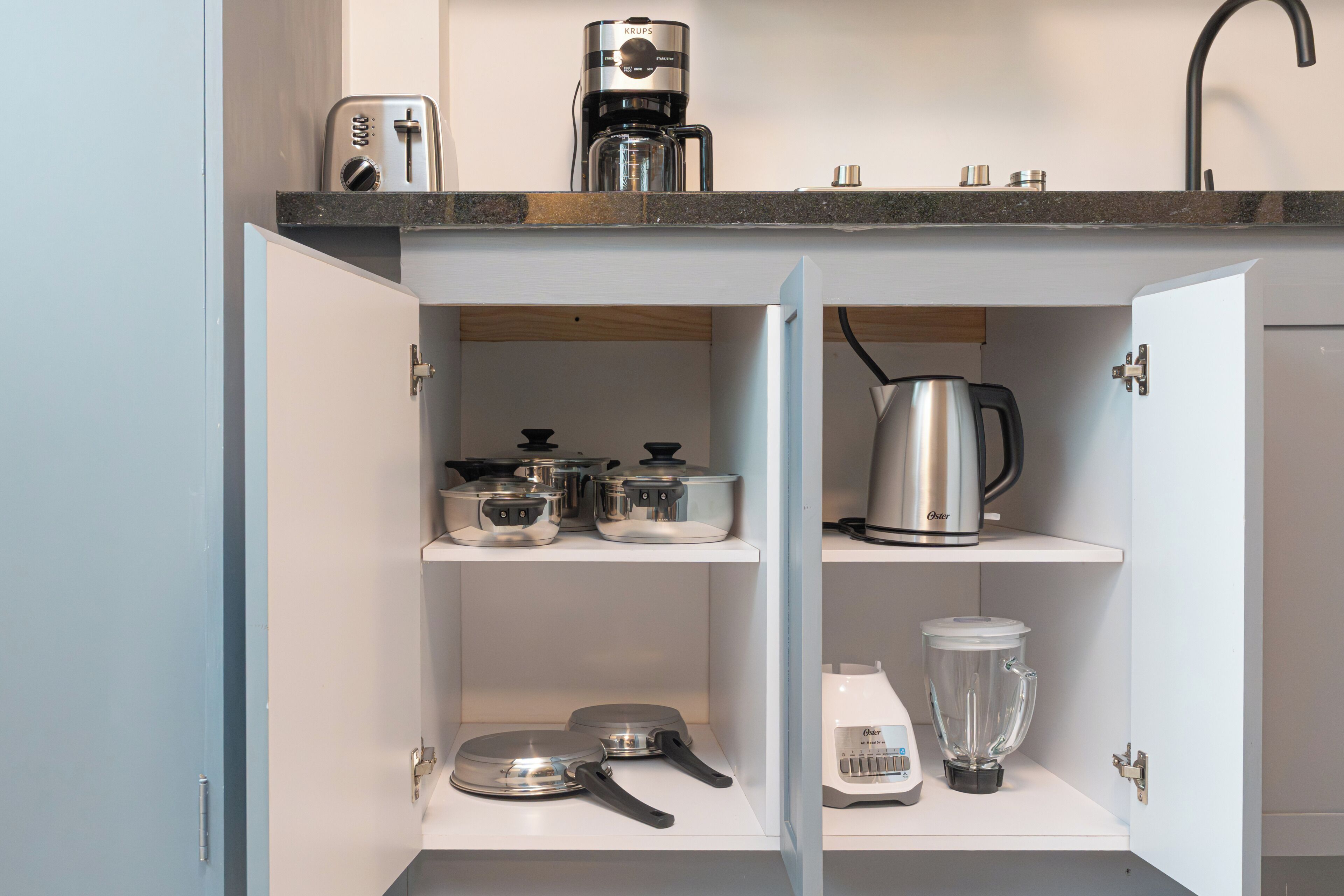 A kitchen with a coffee maker, a kettle, and a blender on the countertop.