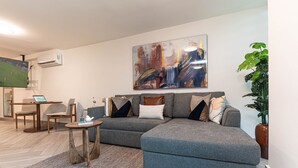 A modern living room with a grey sectional sofa, a small round coffee table, a TV, and a large abstract painting on the wall. - Apartments Homero 538 (Mexico City)