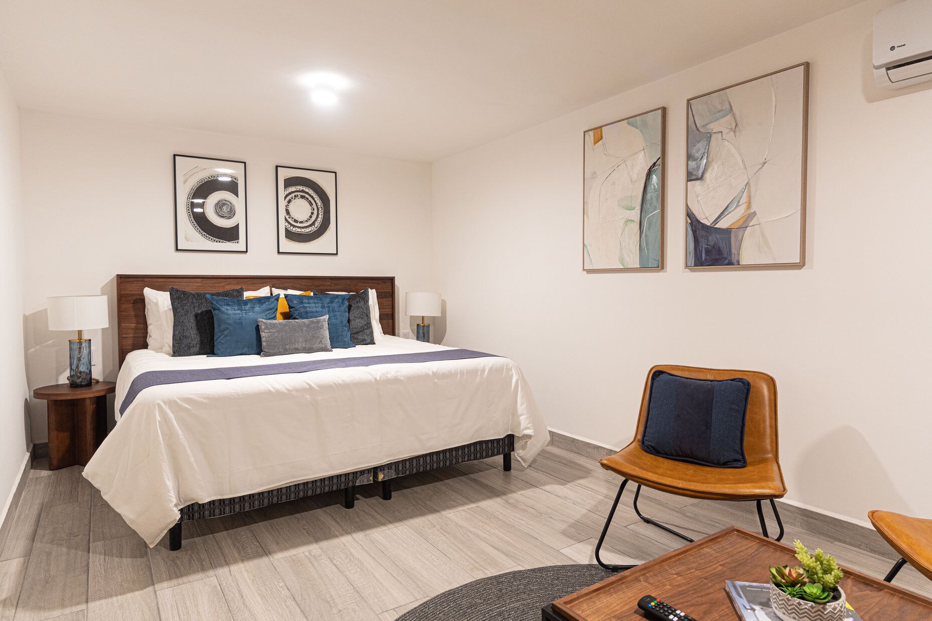 Een hotelkamer met een bed, twee nachtkastjes, een stoel, een salontafel en kunst aan de wanden.