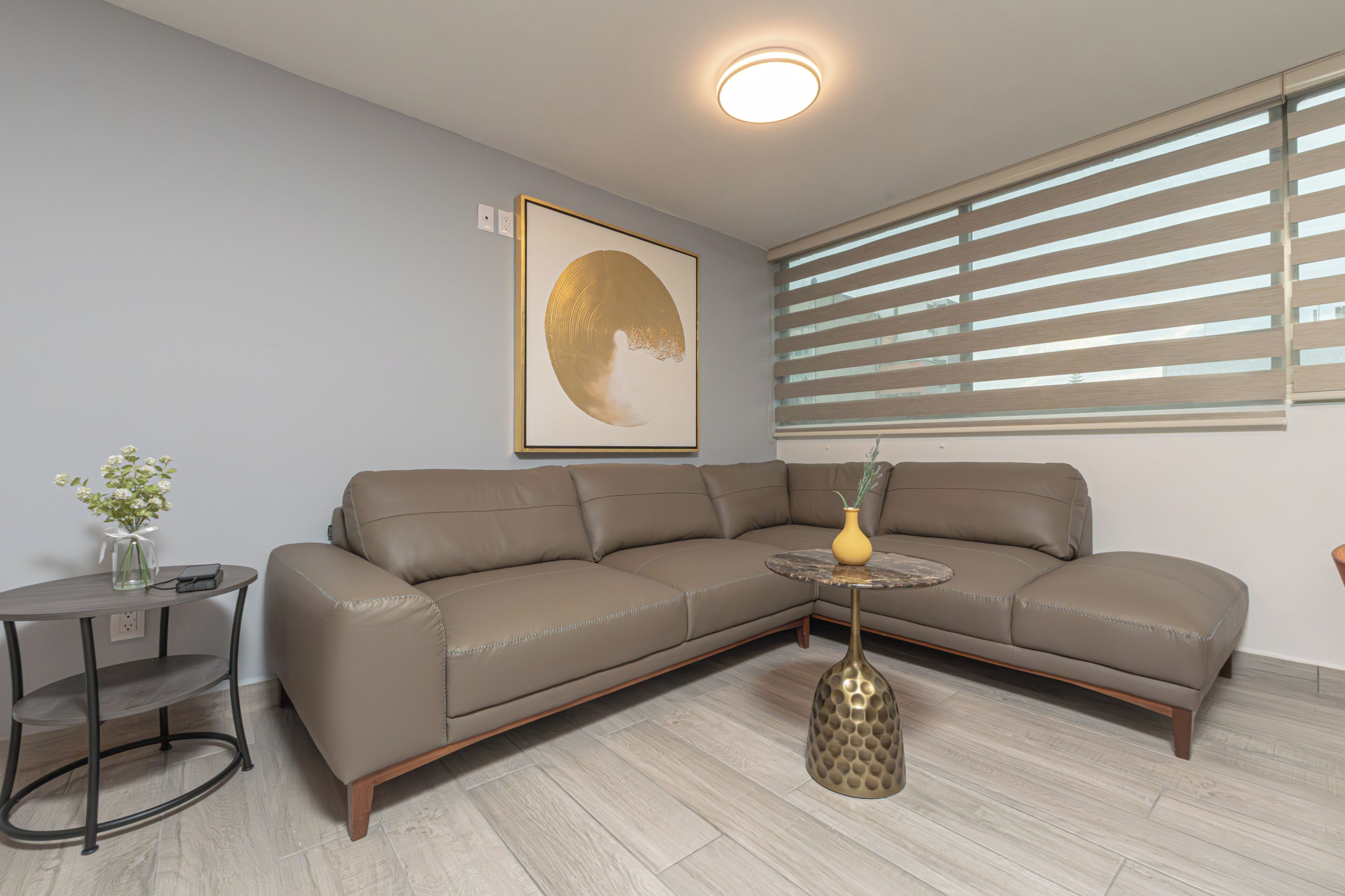 A modern living room with a sectional sofa, a small round table, and a floor lamp.