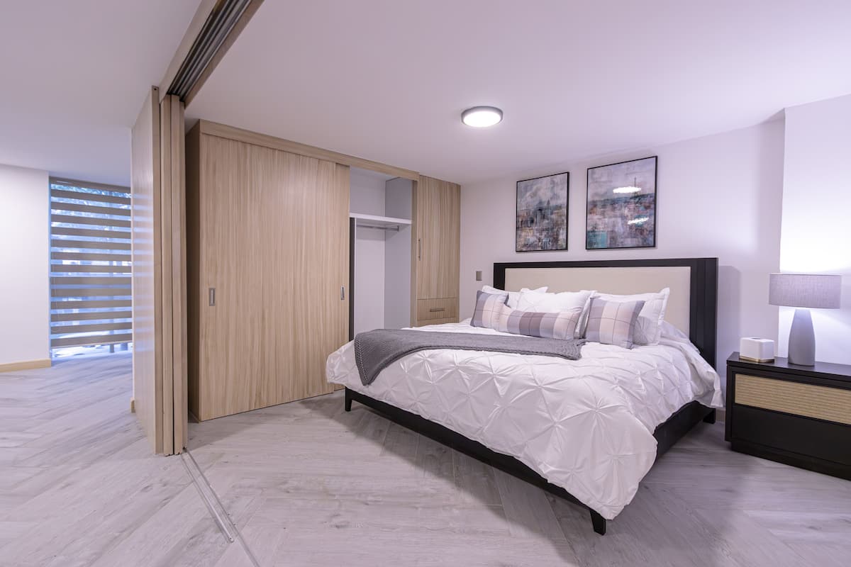 A bedroom with a bed, bedside table, and a wardrobe.