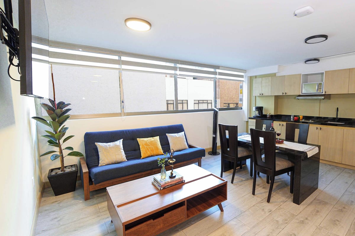 A compact living space with a sofa, dining table, and kitchen area.