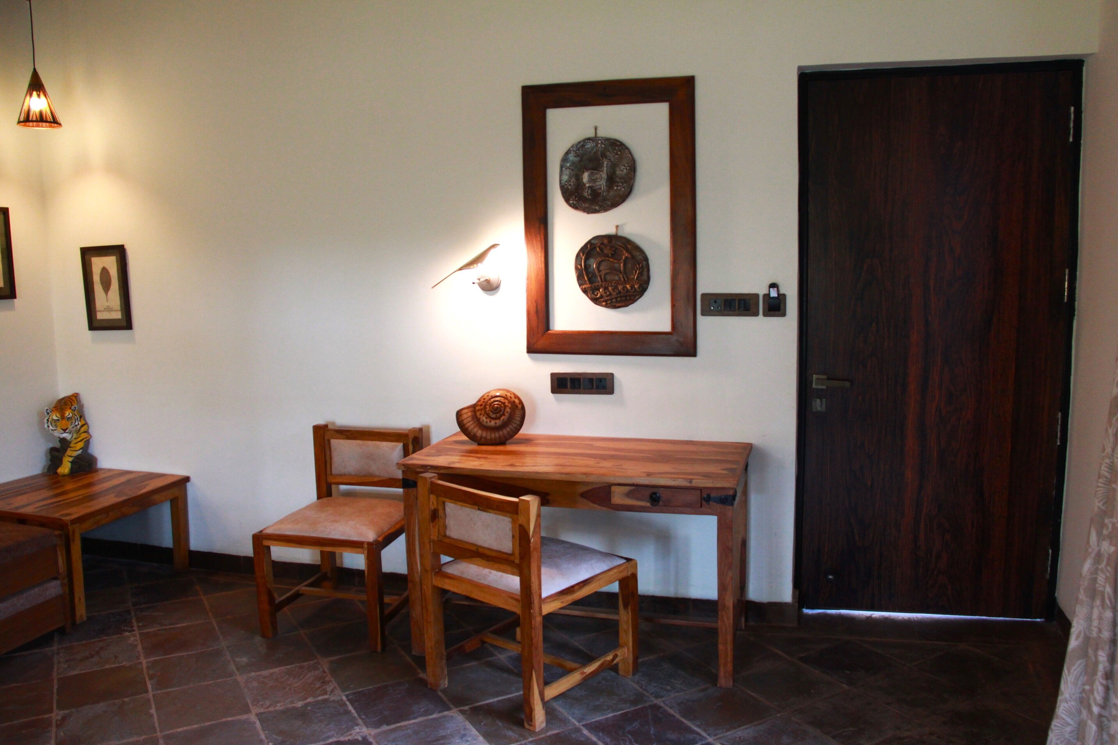 Una mesa de madera con sillas, un banco de madera, un aplique de pared y un cuadro enmarcado.