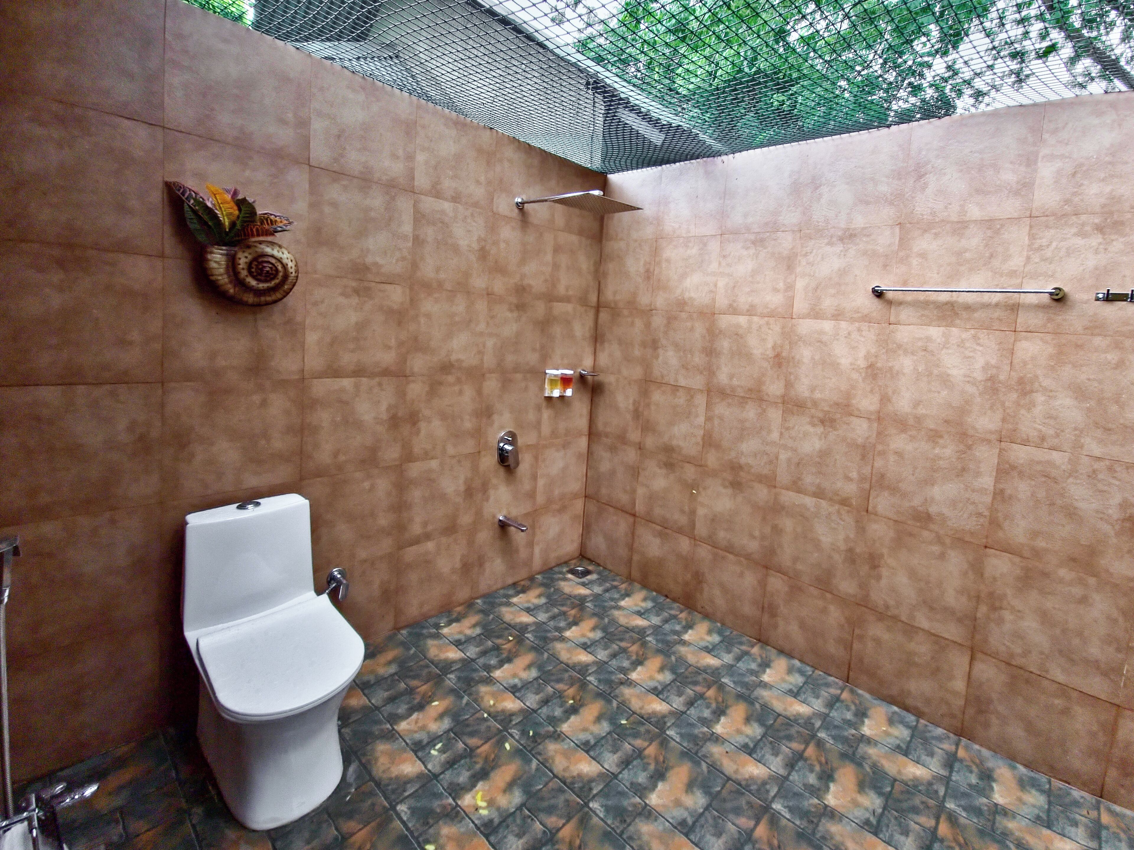 Une petite salle de douche carrelée, équipée de toilettes et d’un porte-serviettes.