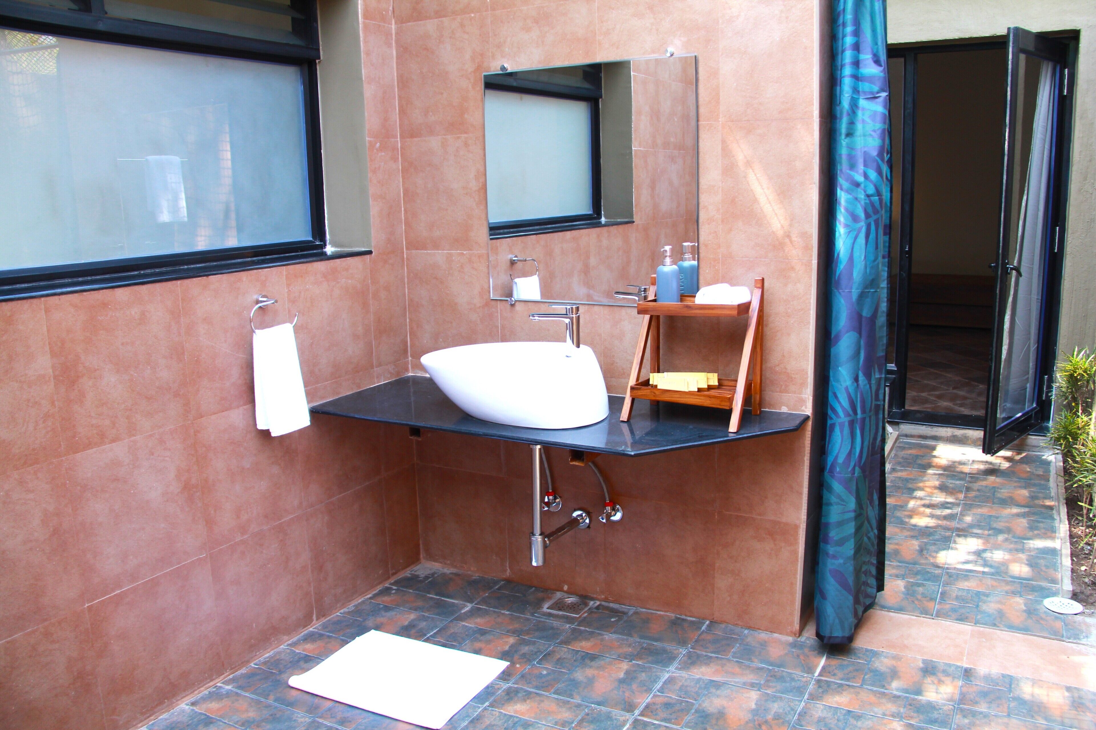 A modern bathroom with a large sink, a mirror, and a shower area.