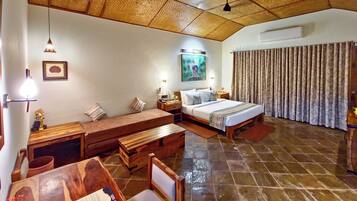 A hotel room with a bed, a desk, a chair, a wooden bench, a dining table, and a tiled floor.