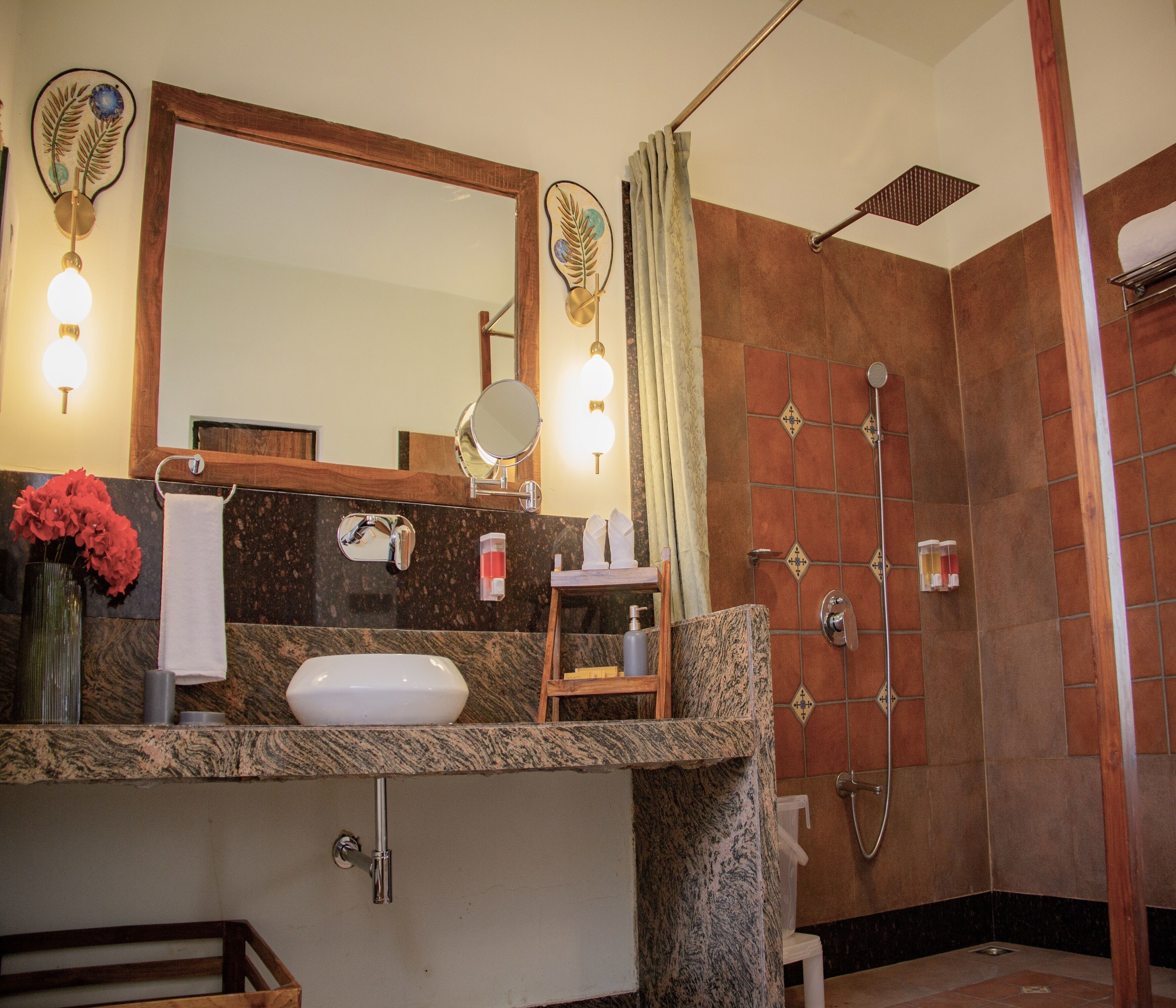 Un bagno con lavandino, specchio, porta asciugamani, doccia e un mobile contenitore con articoli da toilette.
