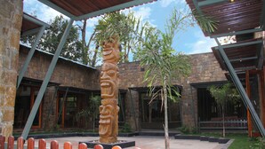 A stone building with large windows and a wooden fence in the foreground. - Tathastu Bandhavgarh (Manpur)