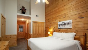 Une chambre à coucher avec une tête de lit en bois, un lit avec une literie blanche, une table de chevet avec une lampe et un tableau accroché au mur.