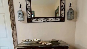 Un gabinete de madera con un espejo encima, un tapete estampado en el frente y una puerta rústica a la izquierda.