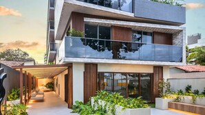 Un edificio moderno de varios pisos con un área exterior cubierta, ventanas amplias y un balcón.