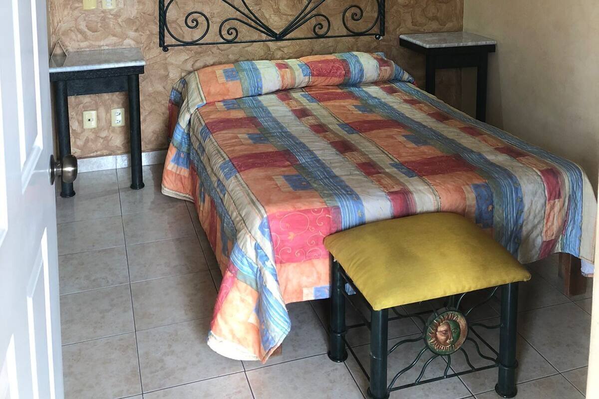 Ein Schlafzimmer mit Bett, einer Sitzbank, einem Deckenventilator und einer Wandleuchte.
