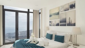Une chambre d’hôtel avec un grand lit, une vue sur la ville et des œuvres d’art accrochées au mur.