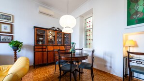 Et spiseområde med et træbord og stole, et skab med glasdøre og en hængende lampe.