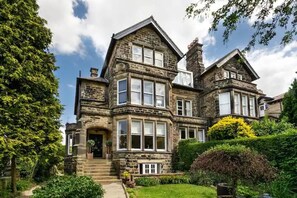 Una casa grande de piedra con varias ventanas y un jardín bien cuidado.