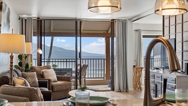 A modern hotel room with a balcony, a dining area, and a view of the sea. - Oceanfront Maui condo with lanai, pool and parking summer deals (Wailuku)