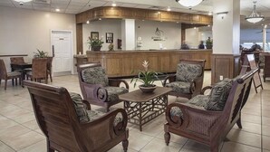 A lobby with wicker furniture, a reception desk, and a wooden counter. - Luxury Coastal Escape Beachfront Daytona Bike Week (Ormond Beach)