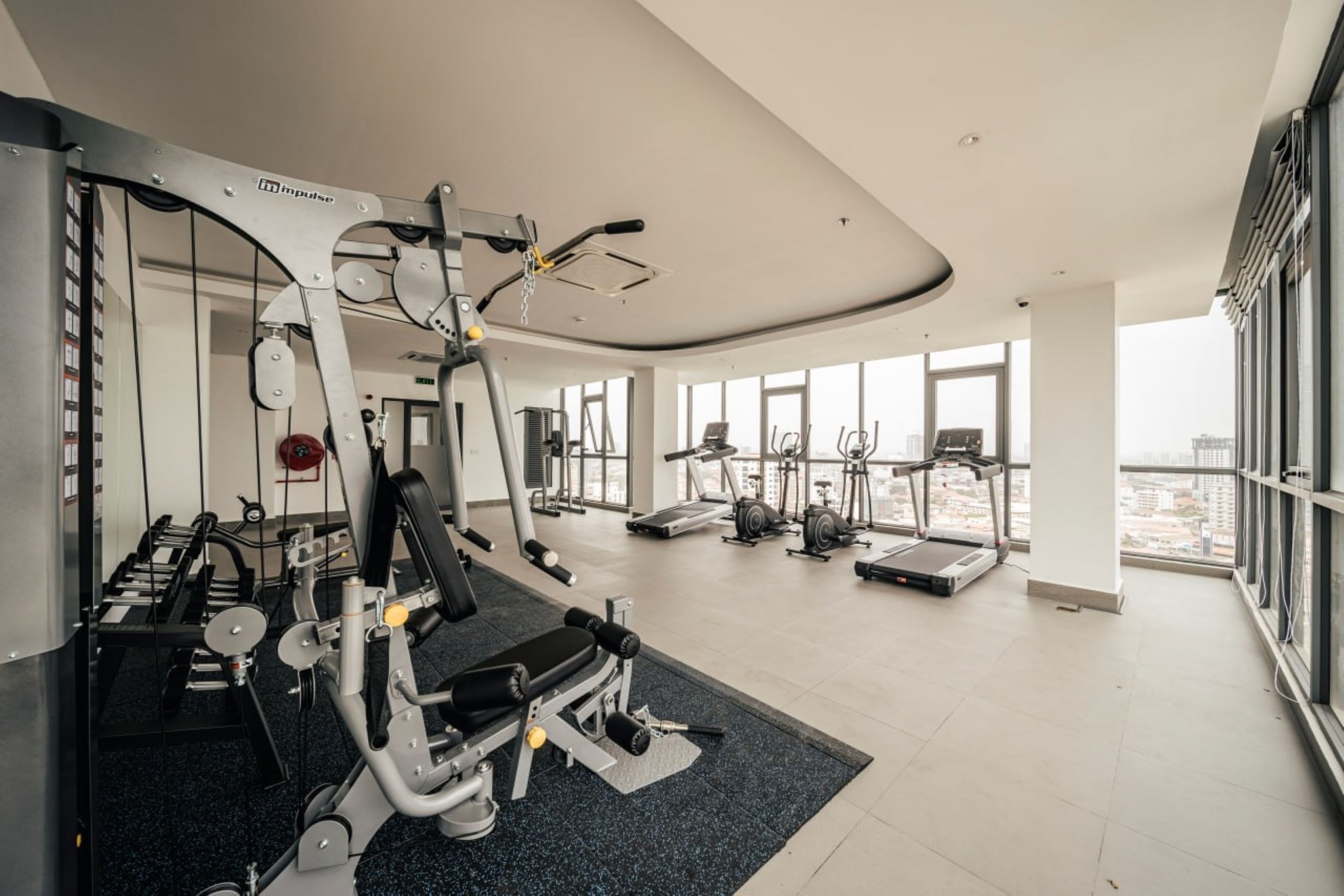 Una palestra moderna con diverse attrezzature per l'allenamento, ampie finestre e vista sulla città.