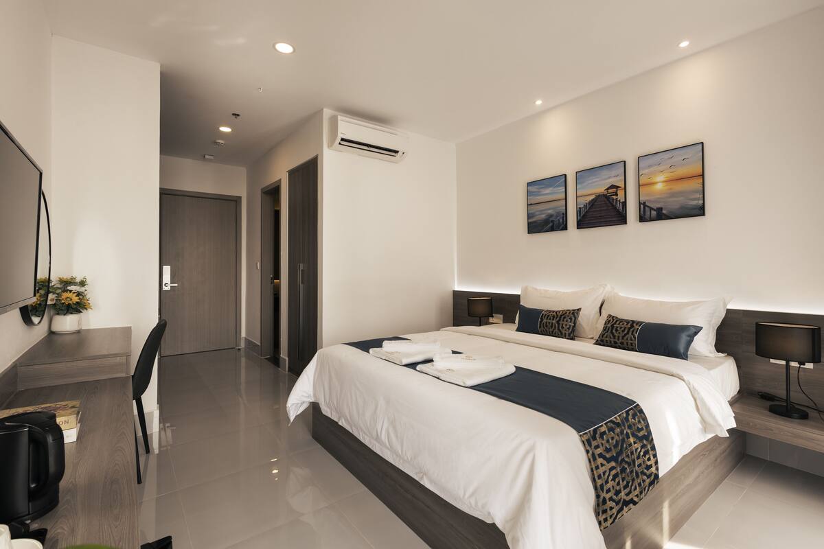 A modern hotel room with a large bed, bedside tables, a desk, and a chair.