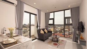 A modern living room with a sofa, a coffee table, and a view of the city. - La Cozii TK (Phnom Penh)