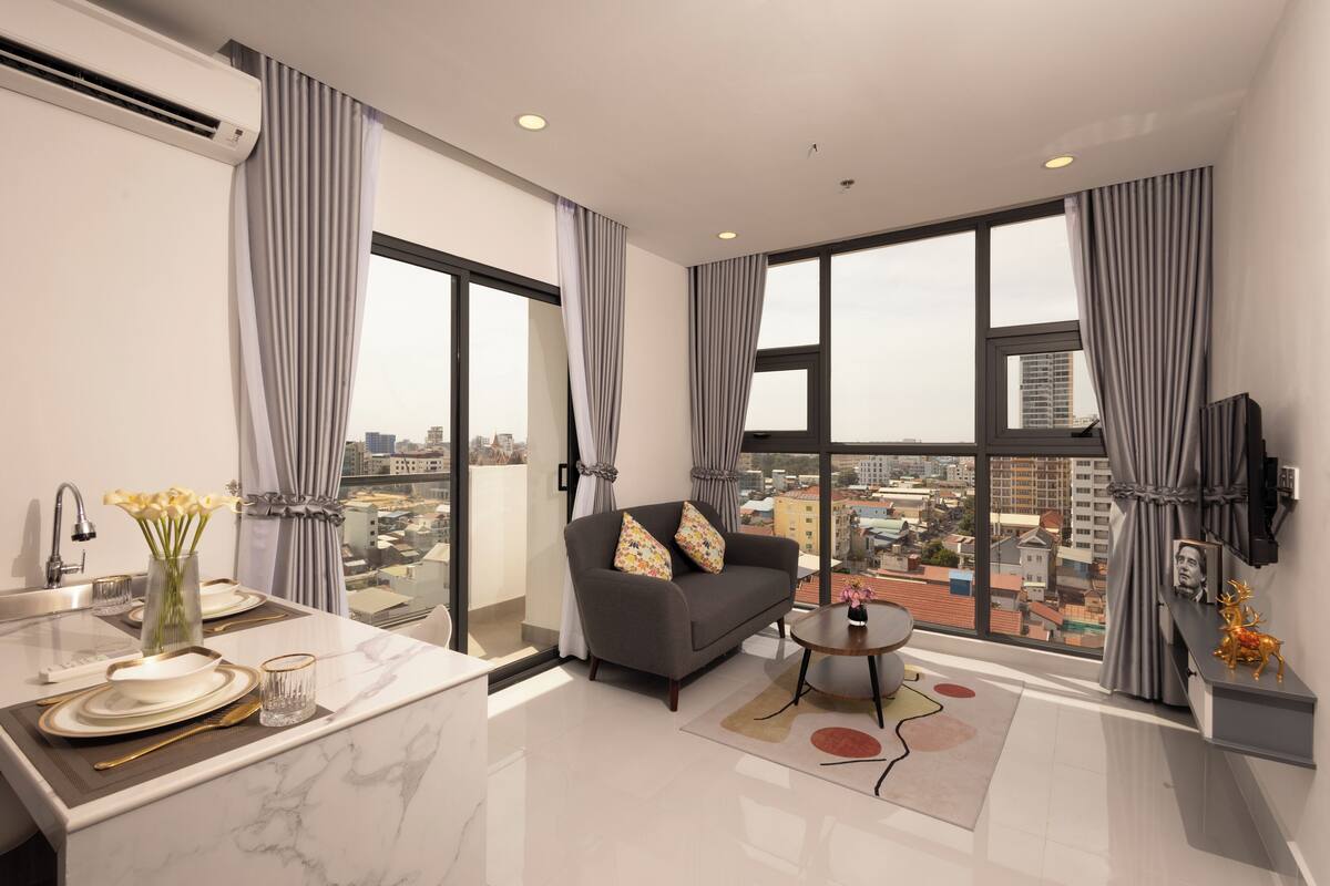 A modern living room with a sofa, a coffee table, and a view of the city.