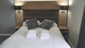 A neatly made bed with two pillows, two bedside tables with lamps, and a headboard. - Stay at the Granary Villa, your home from home. (Shenstone)