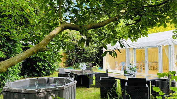 A garden setting with a hot tub, wicker furniture, and a tented area. - Stay at the Granary Villa, your home from home. (Shenstone)