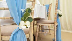 A chair with a blue fabric tied around the backrest, adorned with white flowers. - Stay at the Granary Villa, your home from home. (Shenstone)