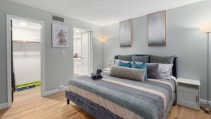 A bedroom with a bed, a nightstand, a lamp, and a door leading to a bathroom. - Pickleball, Pools, Internet, Free Parking, Paradise (Phoenix)