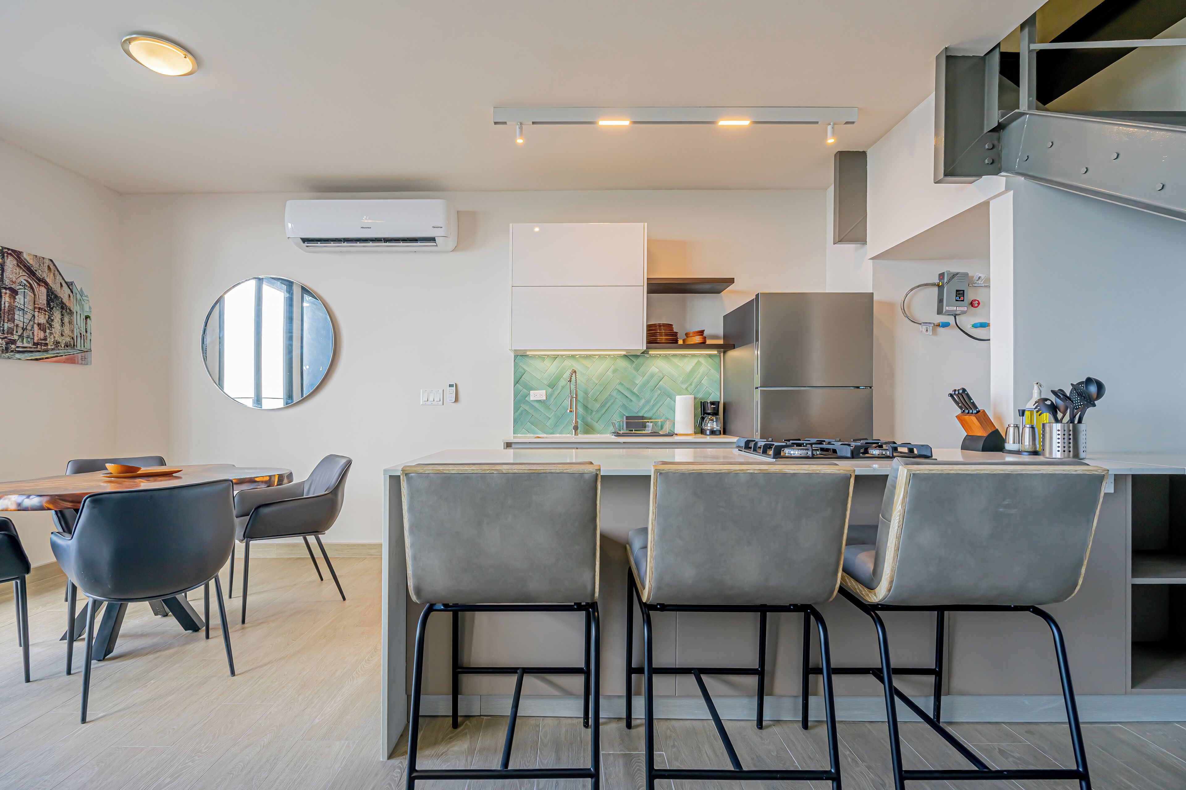 A modern kitchen with a central island, bar stools, and a dining area with a table and chairs.