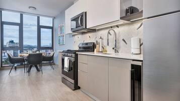 A modern kitchen with a large window, stainless steel appliances, and a dining area with a view.