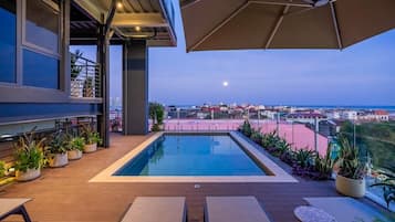 Una piscina al aire libre, sombrillas, sillones reclinables de piscina