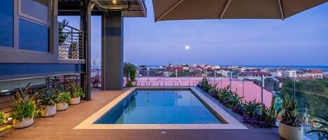 Una piscina al aire libre, sombrillas, sillones reclinables de piscina