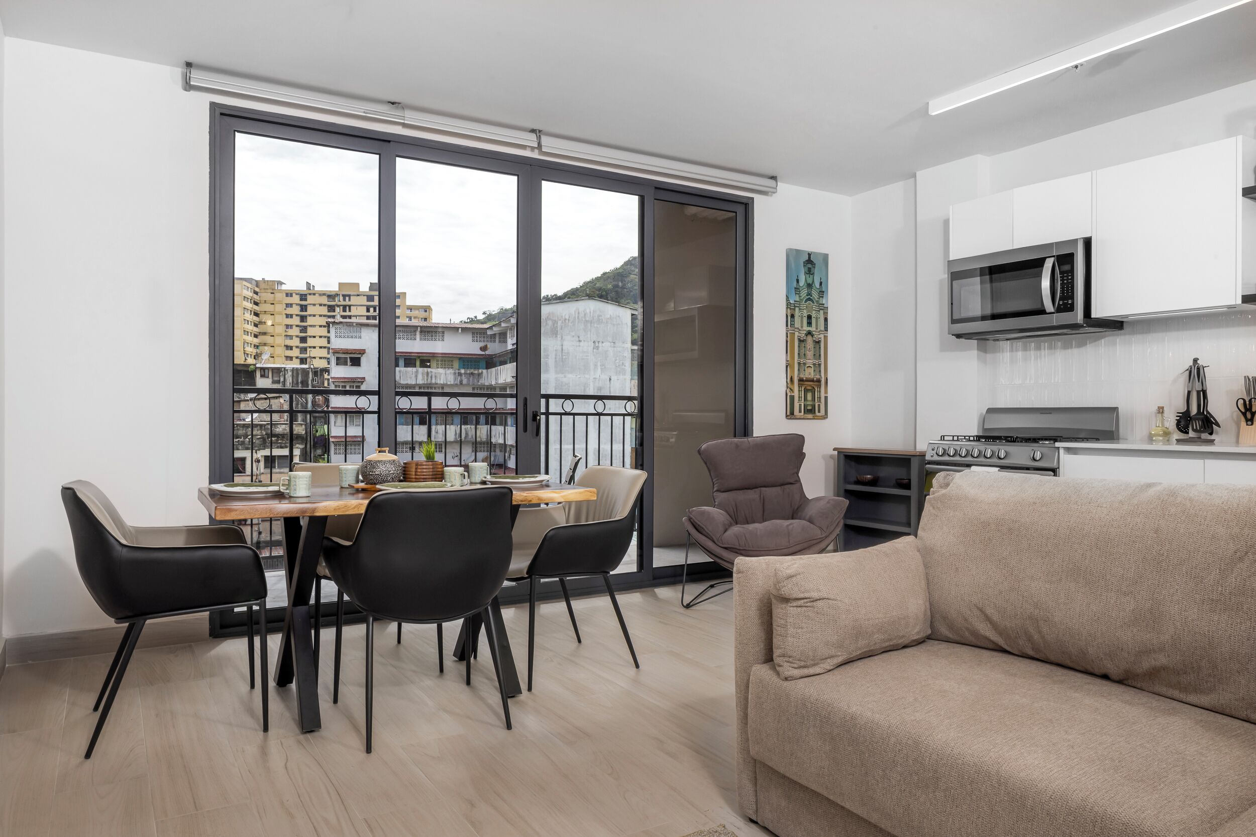 A modern apartment with a dining area, a sofa, a TV, and a kitchen.