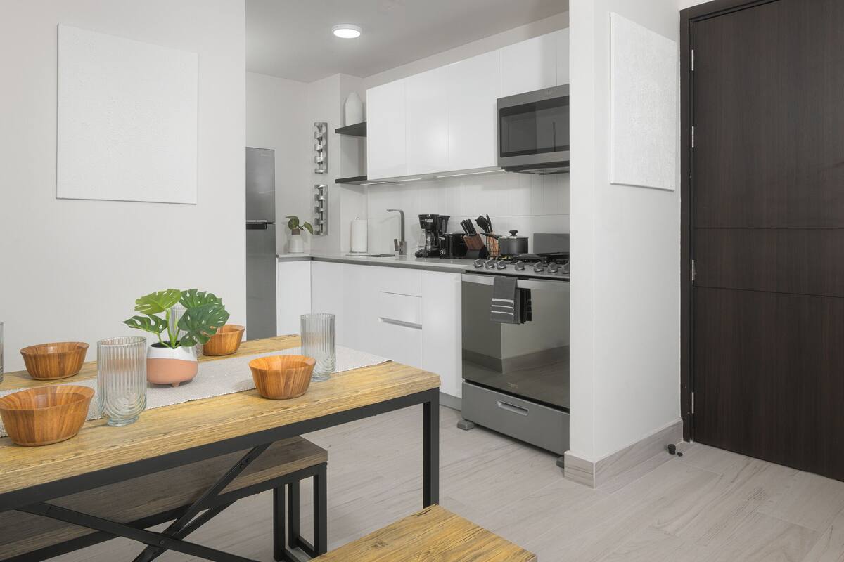 A modern kitchen with white cabinets, stainless steel appliances, and a wooden dining table.
