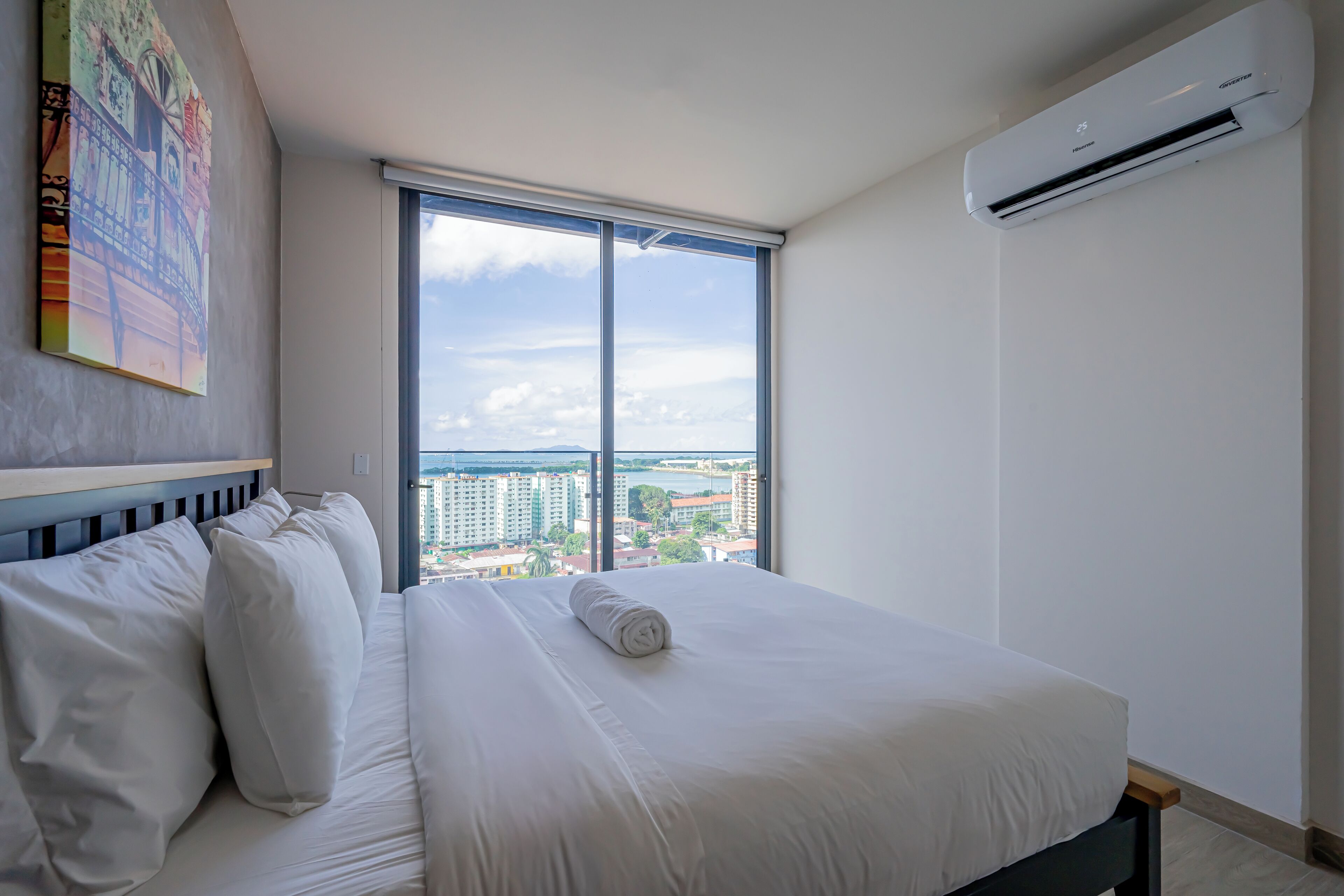 Een hotelkamer met een groot bed, uitzicht op de stad en een airconditioning.