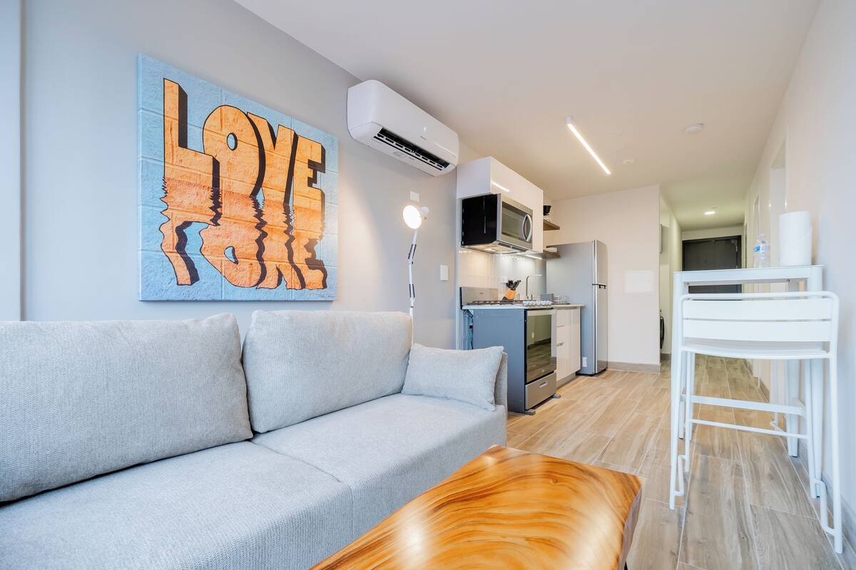 A modern living room with a grey sofa, a wooden coffee table, and a wall-mounted artwork.