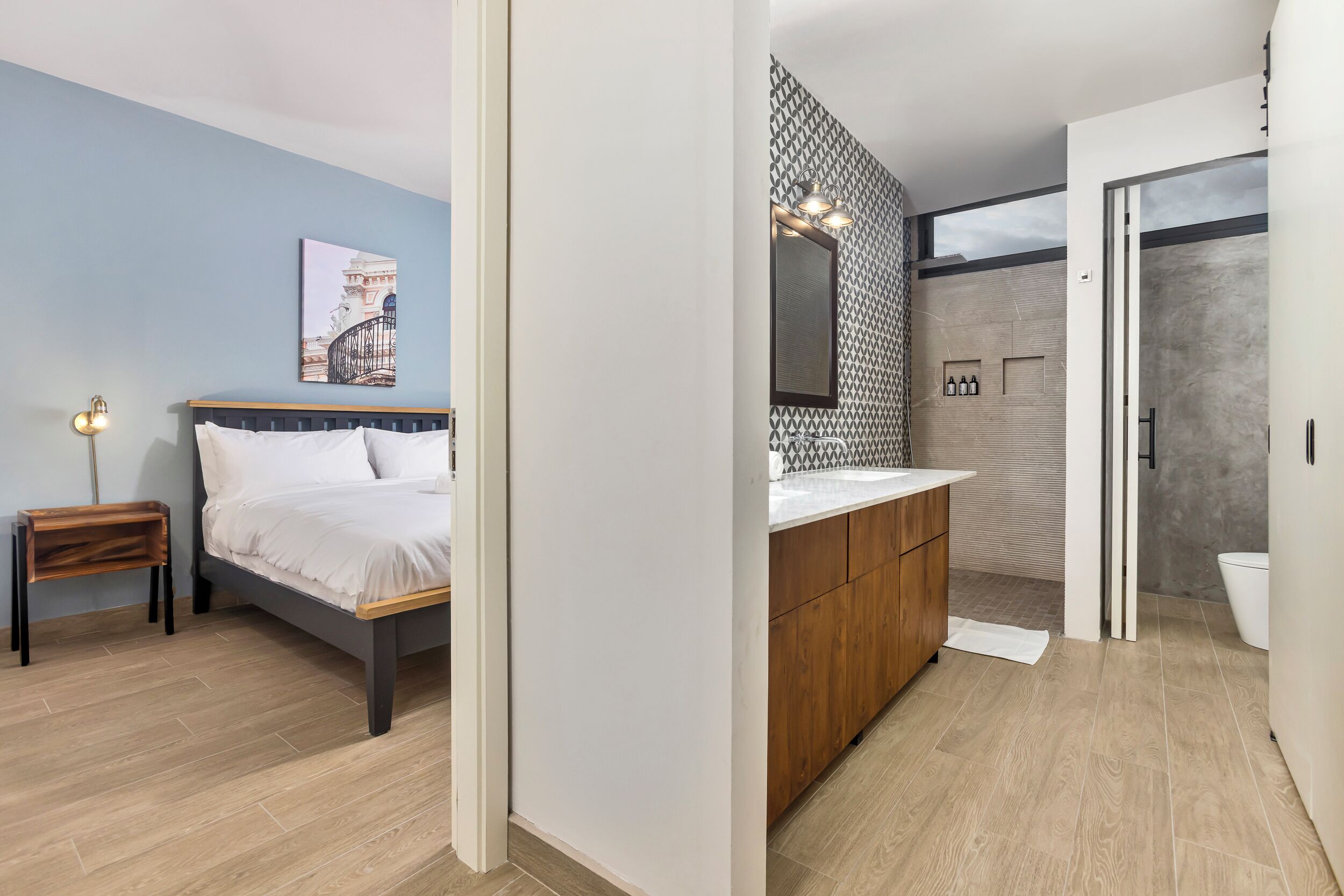 Une chambre d’hôtel moderne équipée d’un lit, d’une table de chevet et d’une salle de bain avec douche, lavabo et toilettes.