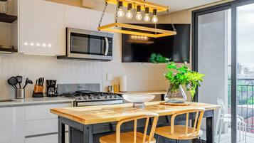 A modern kitchen with a wooden island, stainless steel appliances, and a large window offering a city view.
