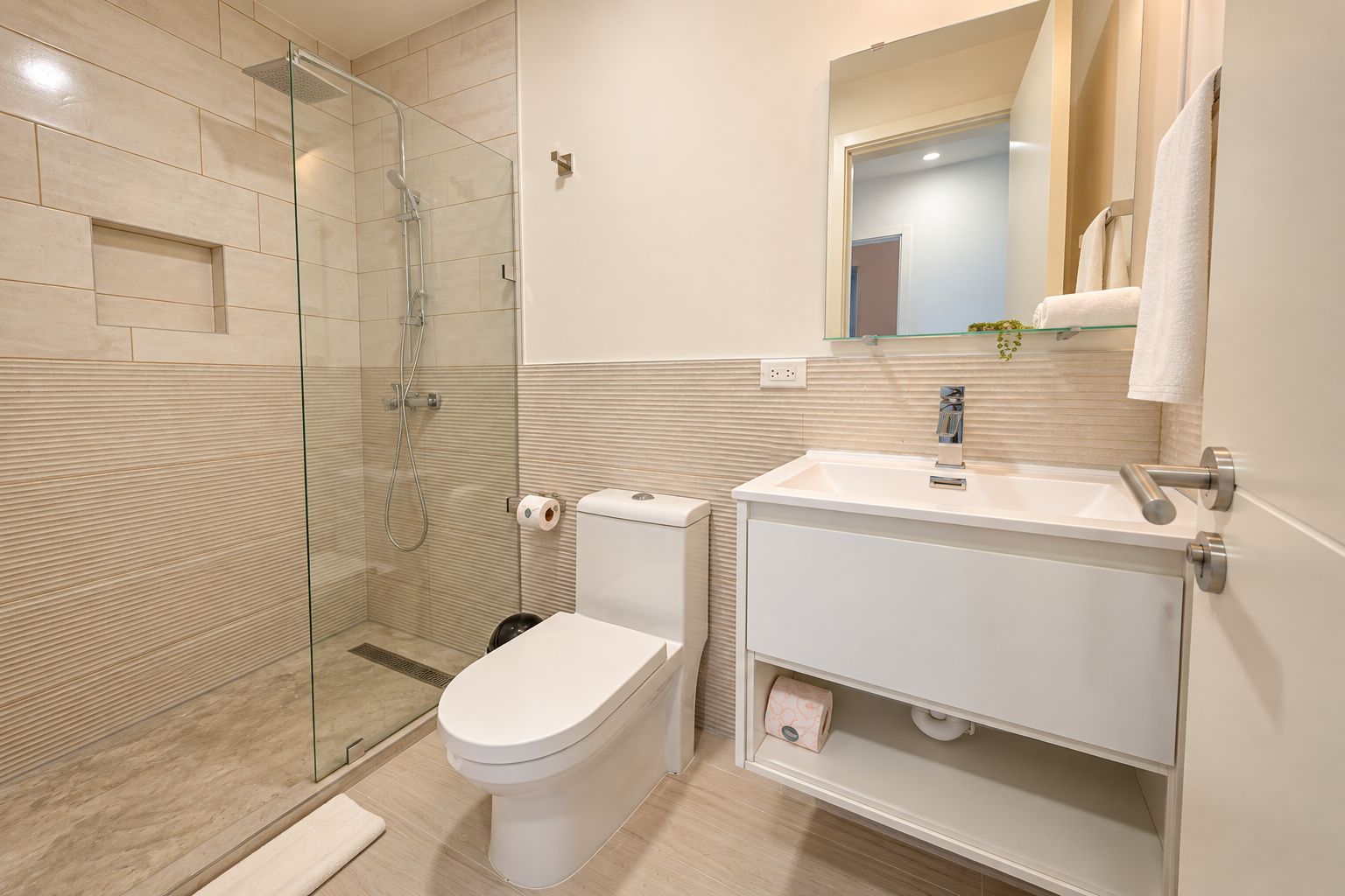 Un baño moderno con cabina de ducha de vidrio, inodoro y lavabo con espejo.